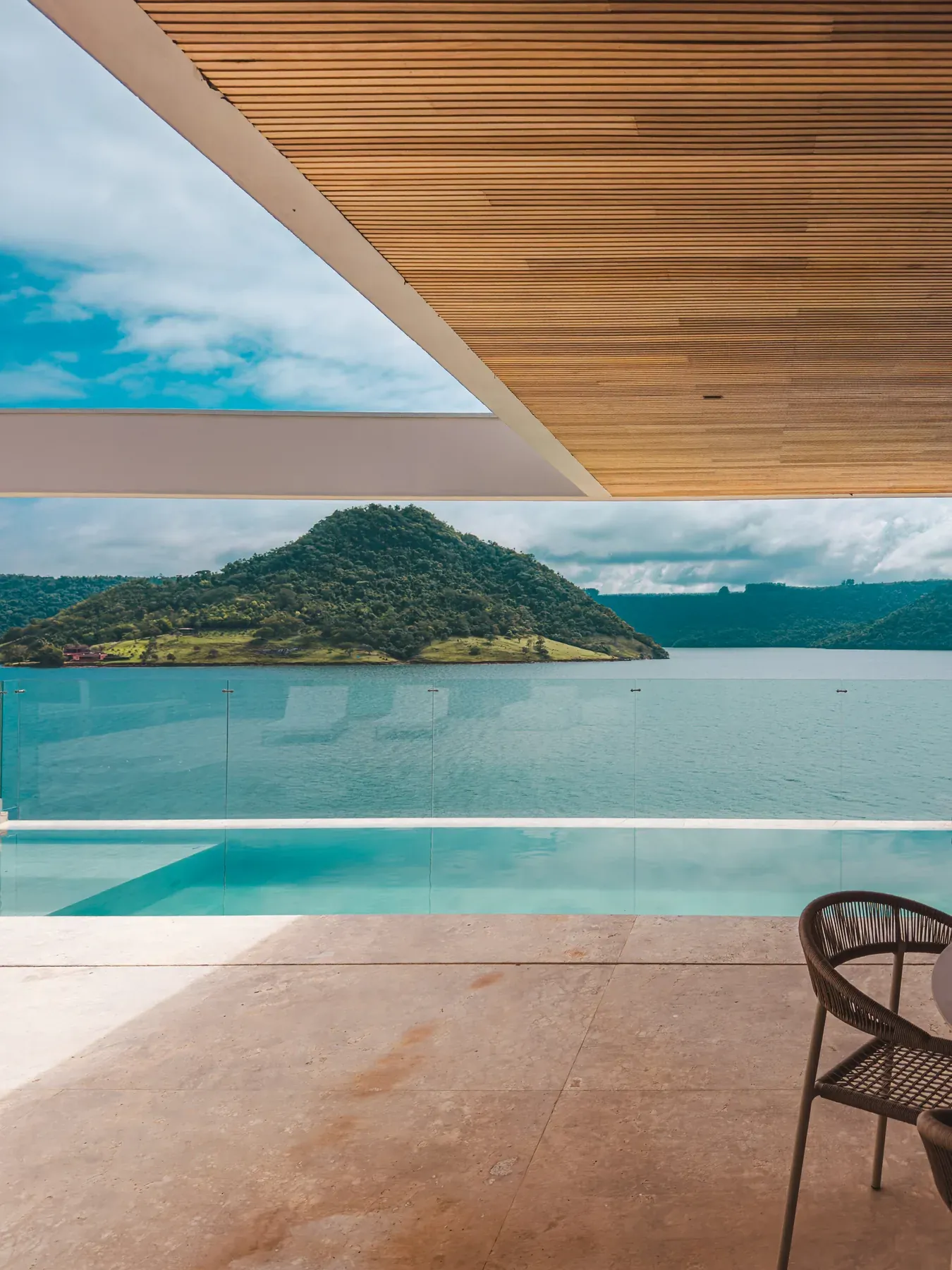 Beiral com forro de madeira sobre a piscina, com o lago ao fundo