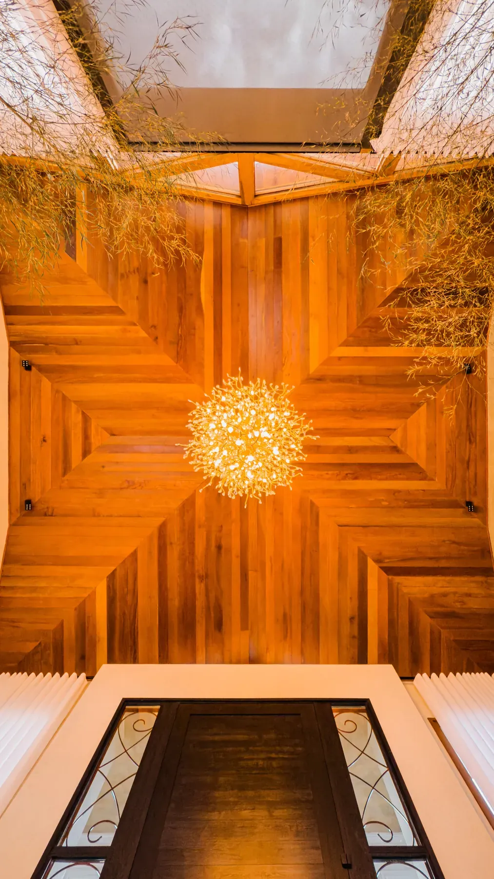 Forro de madeira com desenho em estrela em volta de um lustre